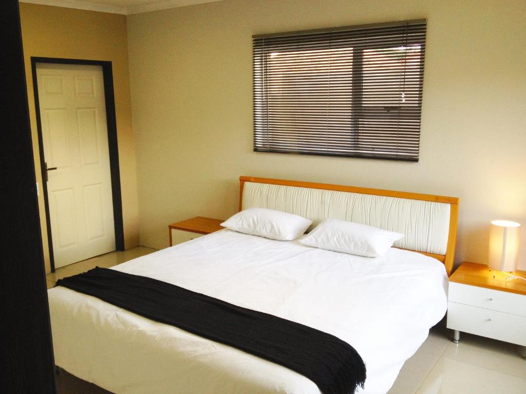 肯普顿帕克AfrikaWisa at O.R. Tambo International Airport的卧室设有一张白色大床和一扇窗户。