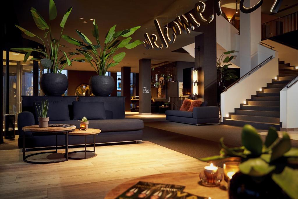 阿尔隆Van Der Valk Luxembourg Arlon的客厅配有蓝色的沙发和盆栽植物
