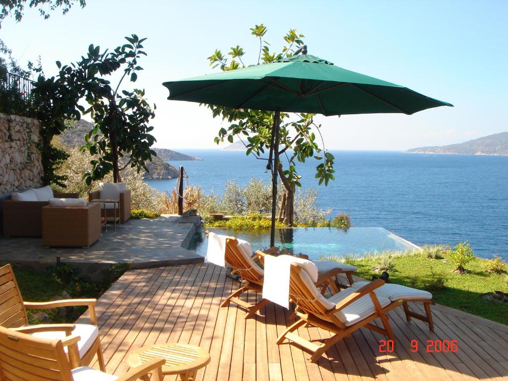 卡尔坎帕塔拉俱乐部别墅的一个带椅子和遮阳伞的庭院和大海