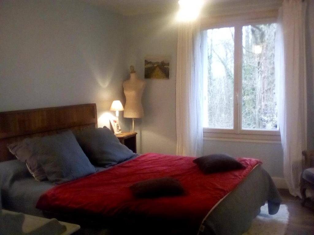 肖蒙La corniche的一间卧室配有一张带红色毯子的床和窗户。
