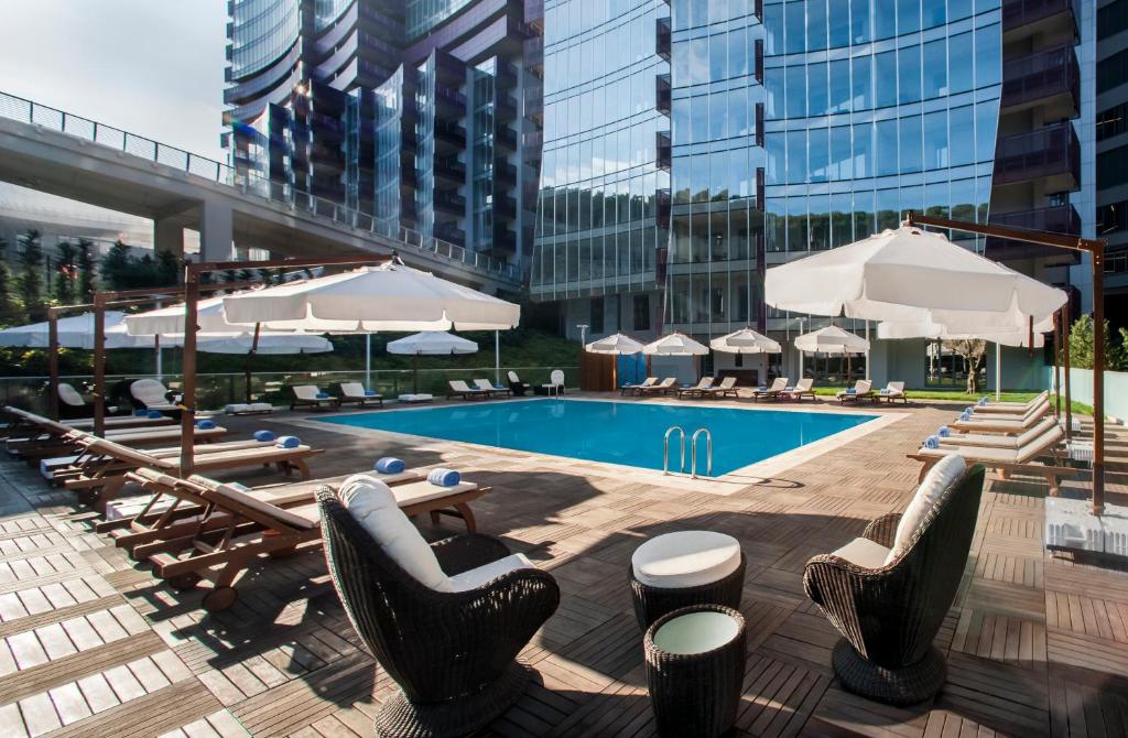 伊斯坦布尔伊斯坦布尔萨默塞特马斯拉克公寓式酒店的一个带桌椅和遮阳伞的游泳池