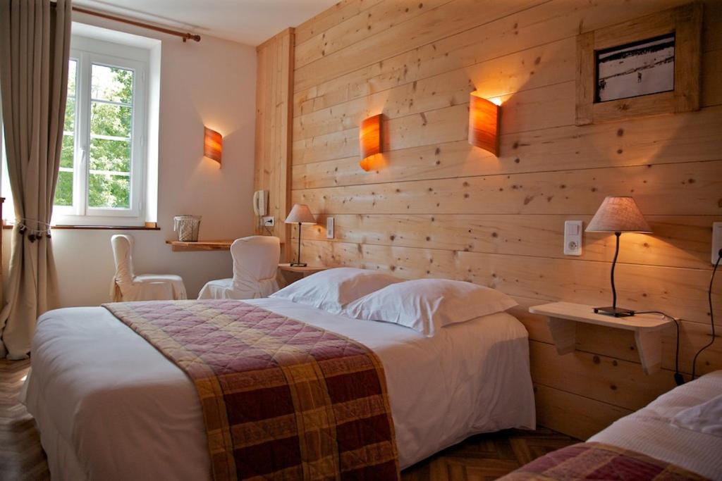 拉穆拉Les Arobiers的酒店客房设有床和木墙