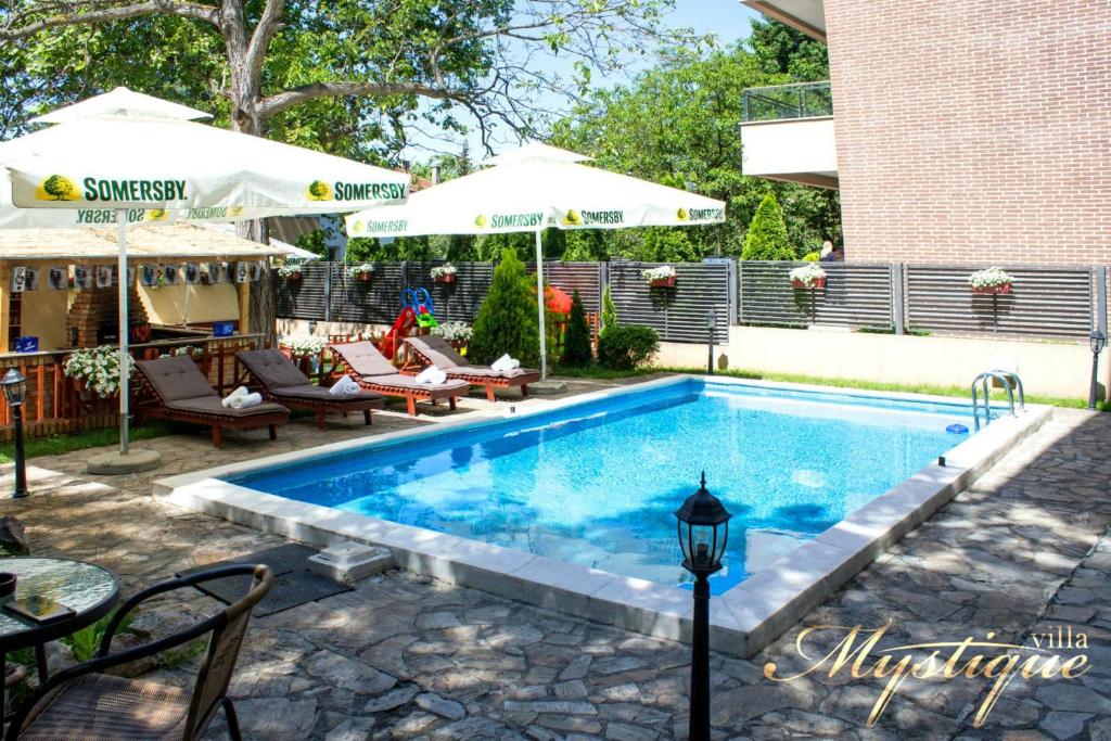 贝尔格莱德奥秘别墅酒店的一座带椅子和遮阳伞的游泳池位于一座建筑旁边