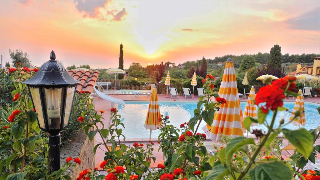 圣温琴佐RTA Costa Etrusca的日落前带遮阳伞和鲜花的游泳池