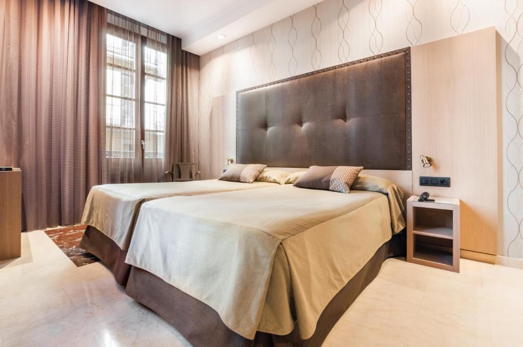 巴塞罗那巴西诺大酒店的一间卧室配有一张大床和大床头板