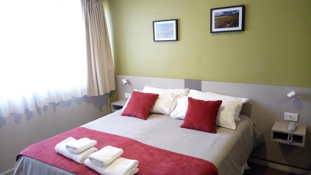 罗卡将军市Estepa Hotel的一间卧室配有一张带红色和白色枕头的大床