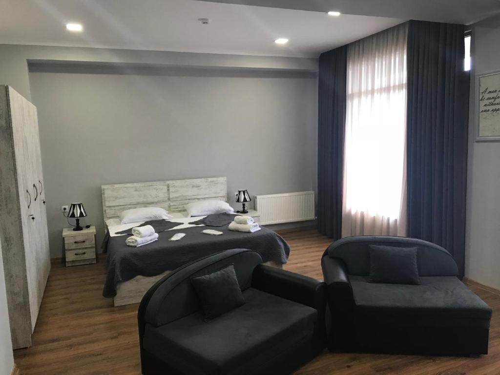 第比利斯Apart Hotel Vera的一间卧室配有一张床、一把椅子和一张沙发
