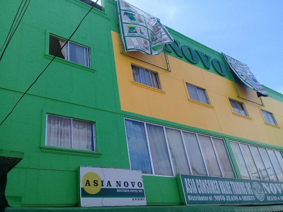 罗哈斯城Asia Novo Boutique Hotel - Roxas的绿色和黄色的建筑,前面有标志