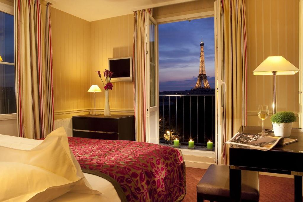 巴黎迪尤肯埃菲尔酒店的一间卧室设有一张床,窗户享有艾菲尔铁塔的景色。