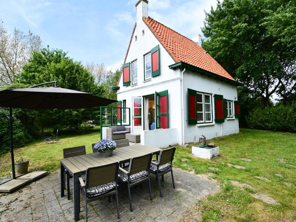 奥德多普Quintessential holiday home in Ouddorp with garden的房屋配有桌椅和遮阳伞