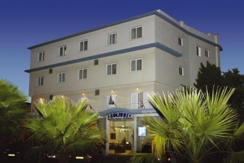 卡帕里卡海岸科利柏酒店的一座白色的大建筑,前面有棕榈树