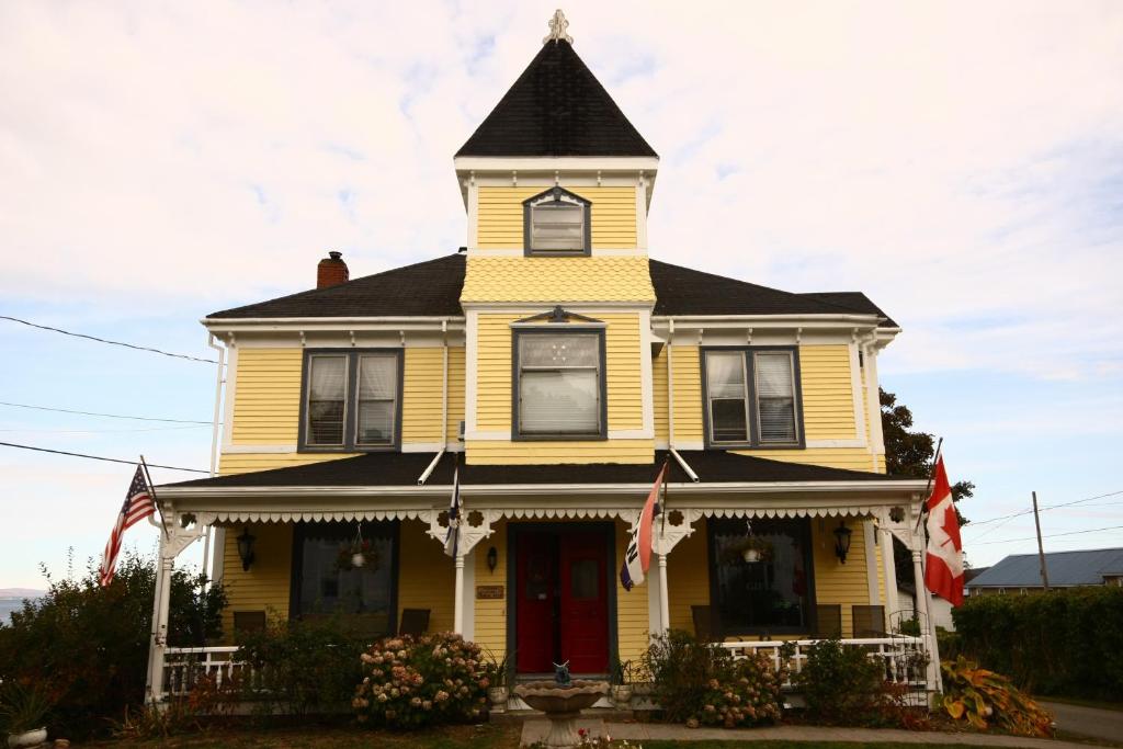 迪格比归来住宿加早餐旅馆的黄色的房子,有黑色的屋顶和红色的门