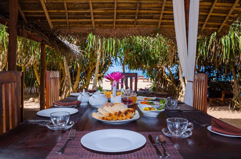 阿洪加拉Jungle Beach Ahungalla的一张木桌,上面放着食物盘