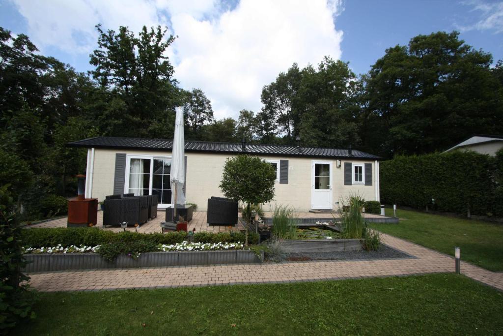 瓦赫宁根Vakantiehuis Veluwe Wageningen的一座白色的小房子,前面设有一个花园