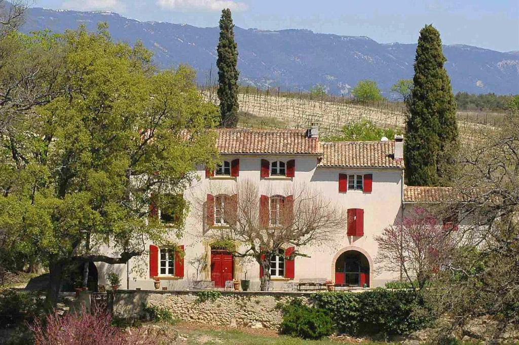卡代纳La Tuilière en Luberon的一座白色的大房子,有红色的门和树木