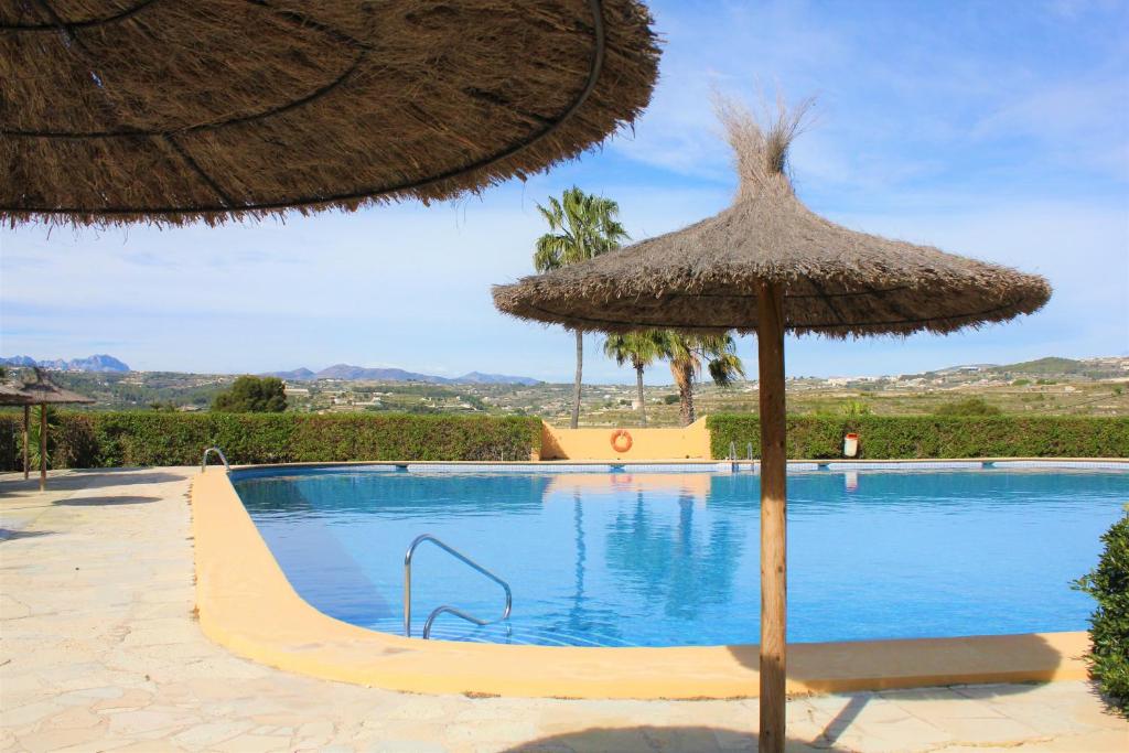 莫莱拉Villa Larosa的一个带草伞的游泳池和一个游泳池