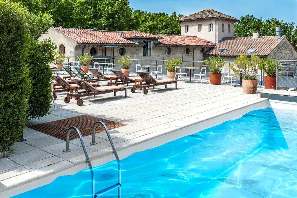 阿维尼翁克鲁尔特圣路易斯阿维农酒店的一个带椅子的游泳池以及一座房子