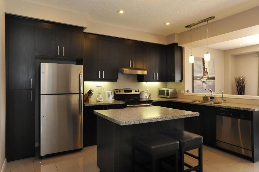 基奇纳浮桥之家行政旅馆的厨房配有黑色橱柜和不锈钢冰箱