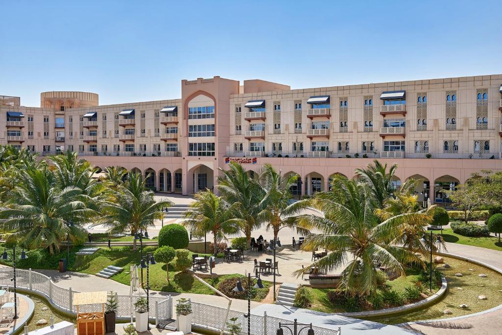 塞拉莱Salalah Gardens Hotel Managed by Safir Hotels & Resorts的一座棕榈树环绕的大建筑