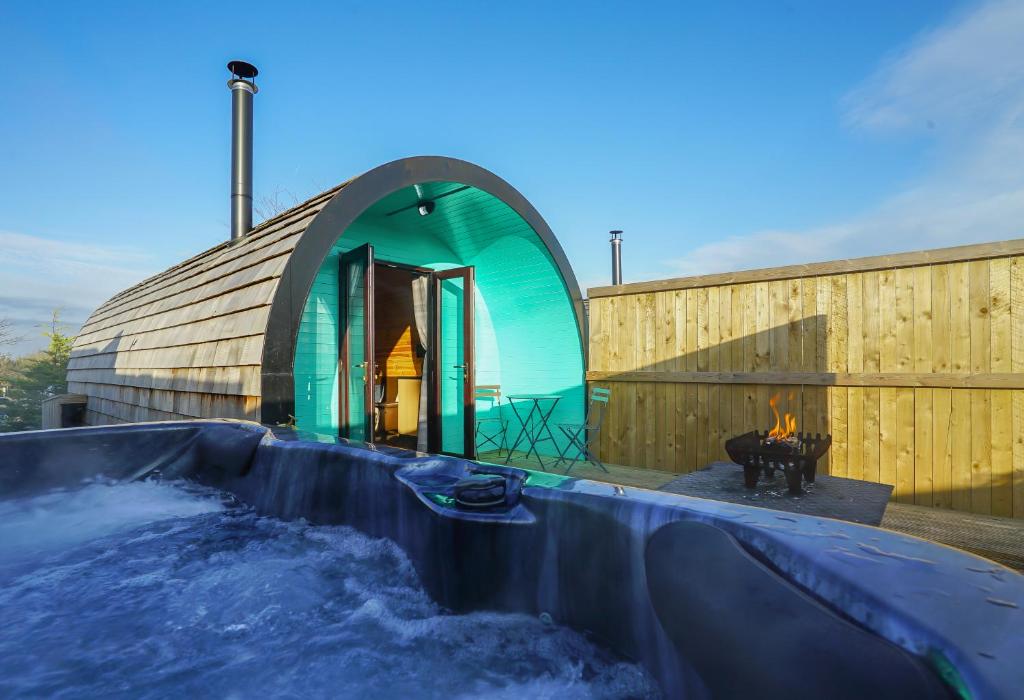 弗罗德舍姆Deluxe Glamping Pod with Hot Tub的一座带水池和壁炉的建筑