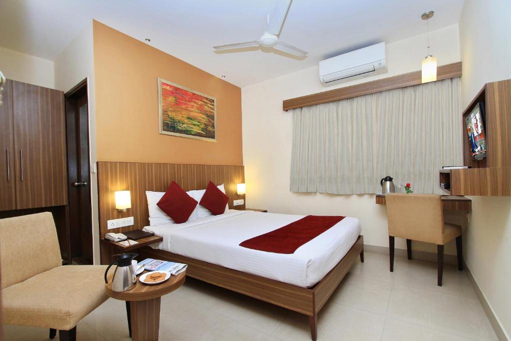 班加罗尔La Sara Comforts的酒店客房配有一张床、一张桌子和一把椅子。