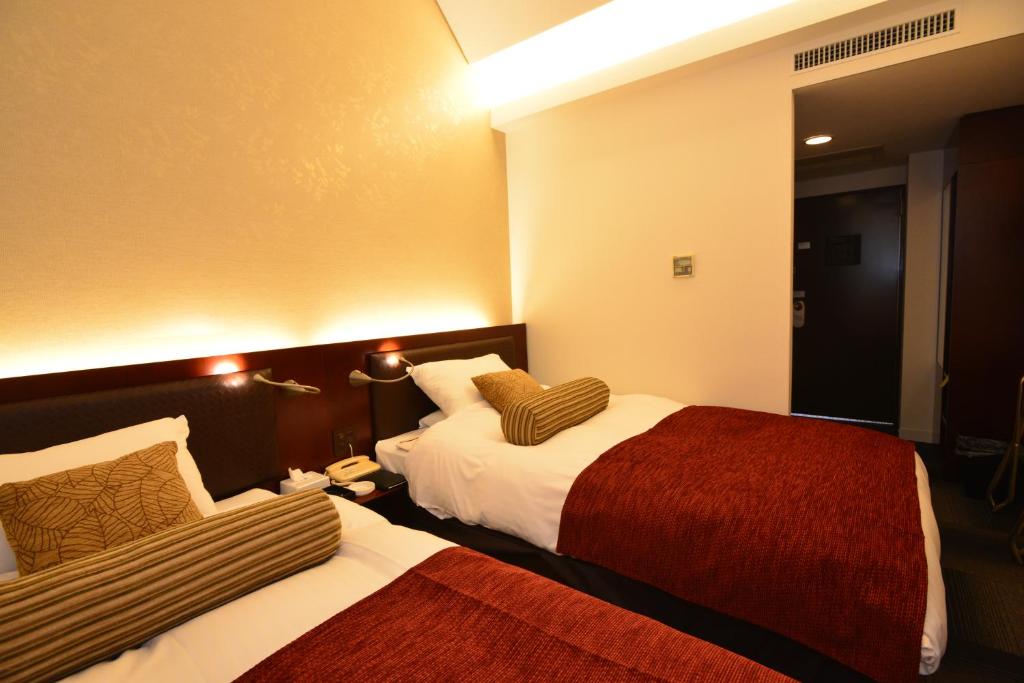 橿原市橿原市大和酒店的酒店客房,设有两张床和镜子