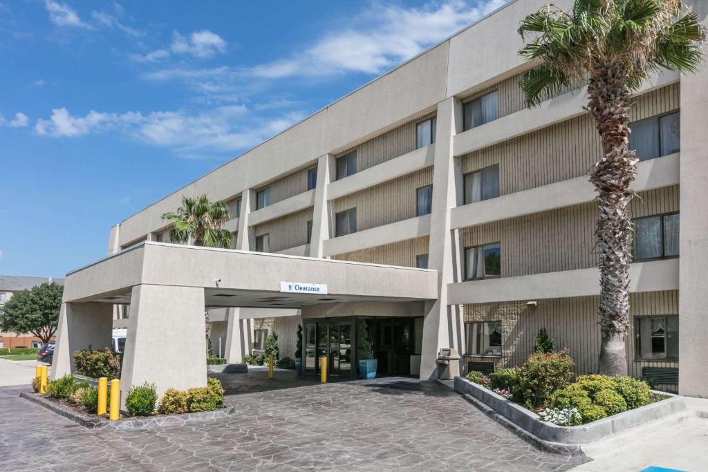 阿林顿阿灵顿DFW六旗大道贝蒙特旅馆套房酒店的一座棕榈树环绕的大建筑