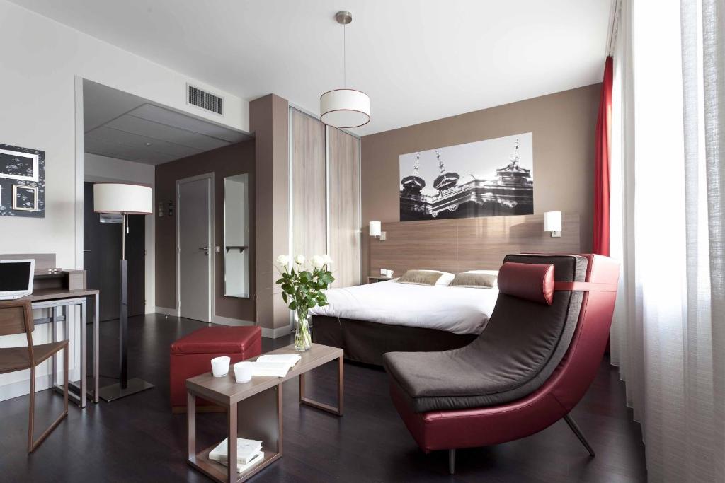 圣艾蒂安圣艾蒂安城市阁楼公寓式酒店的酒店客房,配有一张床和一张红色椅子