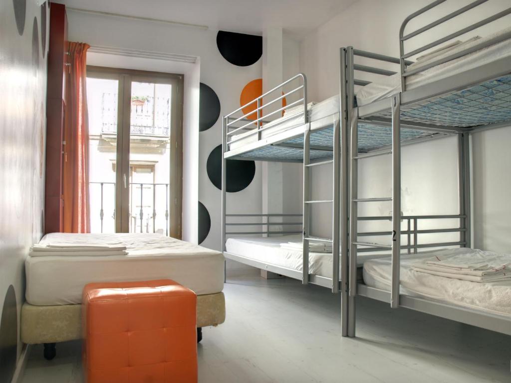 萨拉曼卡Albergue Revolutum Hostel的带两张双层床和橙色凳子的房间