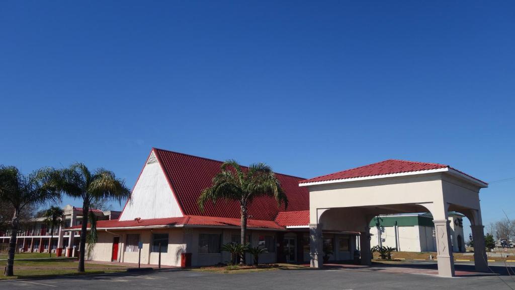 艾伦港Baton Rouge West Inn的一个带红色屋顶和棕榈树的加油站
