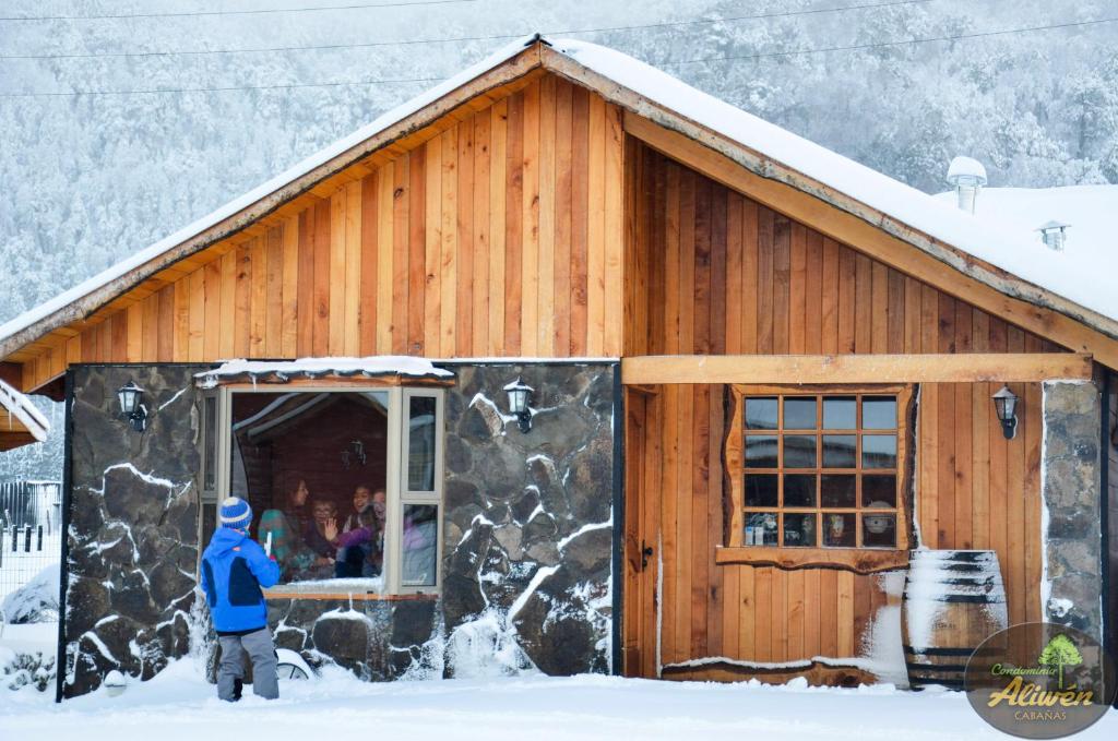 马拉卡韦罗Condominio Aliwén Cabañas的站在建筑物外的雪中的人