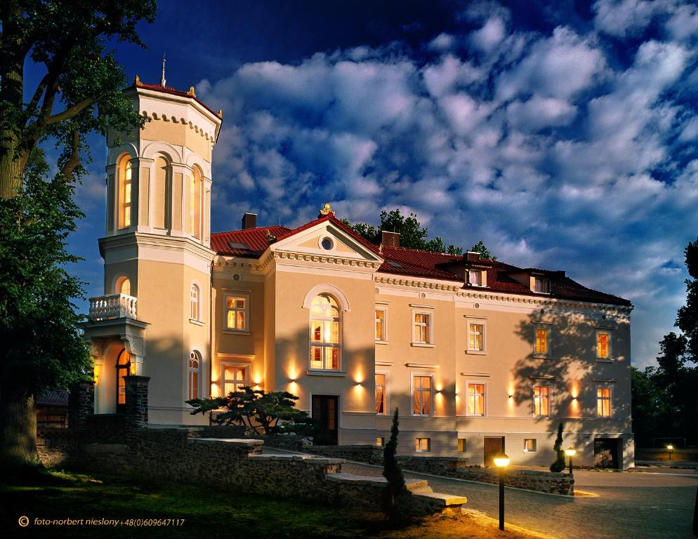 GorzPałac Pawłowice的一座白色的大建筑,晚上有塔楼