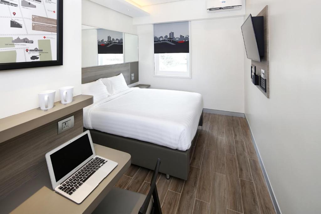 马尼拉Red Planet Cubao Aurora Boulevard的酒店客房配有一张床铺和一张书桌上的笔记本电脑