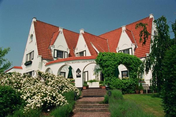 德哈恩及时行乐浪漫庄园酒店的一座大型白色房屋,设有红色屋顶