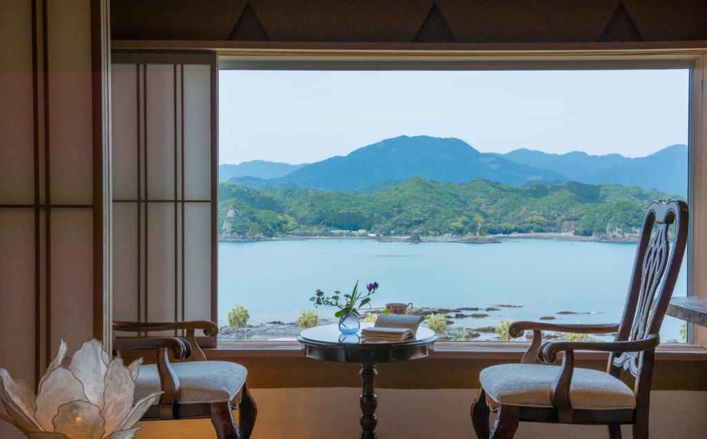 太地町花彩之宿花游传统日式旅馆的客房设有带桌椅的大窗户。
