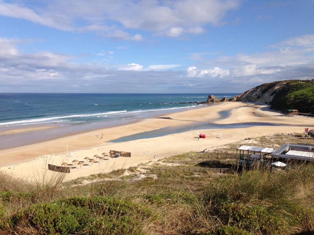 帕塔亚什Apartamento acolhedor numa das mais belas praias do centro de Portugal的沙滩上,有遮阳伞和大海