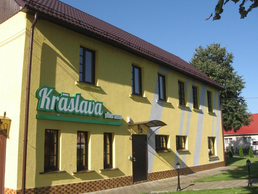 克拉斯拉瓦Hotel in Kraslava的黄色和白色的建筑,上面有标志