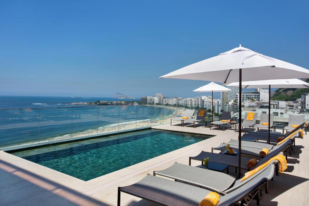 里约热内卢Windsor California Copacabana的一座大楼内的游泳池,配有椅子和遮阳伞