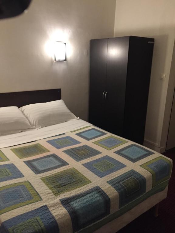 勒瓦卢瓦-佩雷舍瓦利尔酒店的一间卧室配有一张床和一个黑色橱柜