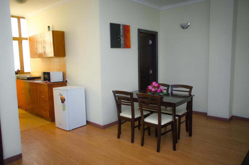 亚的斯亚贝巴Union Hotel Apartments的厨房配有桌椅和冰箱。
