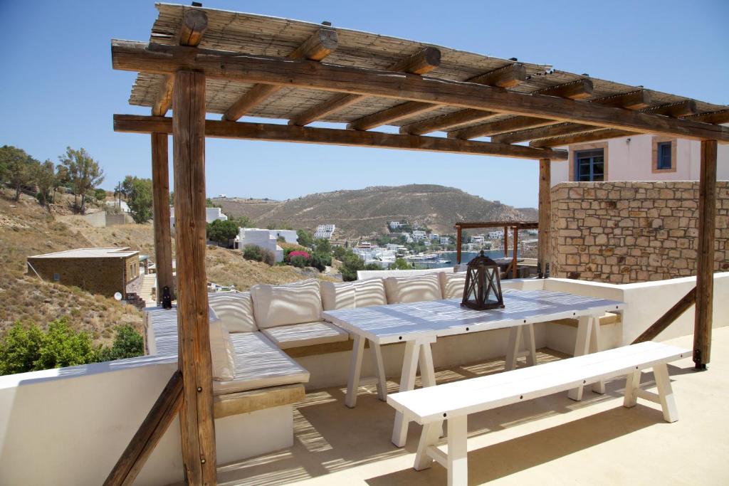 GrikosLuxury house in the island of Patmos的庭院设有木制凉亭、桌子和长凳