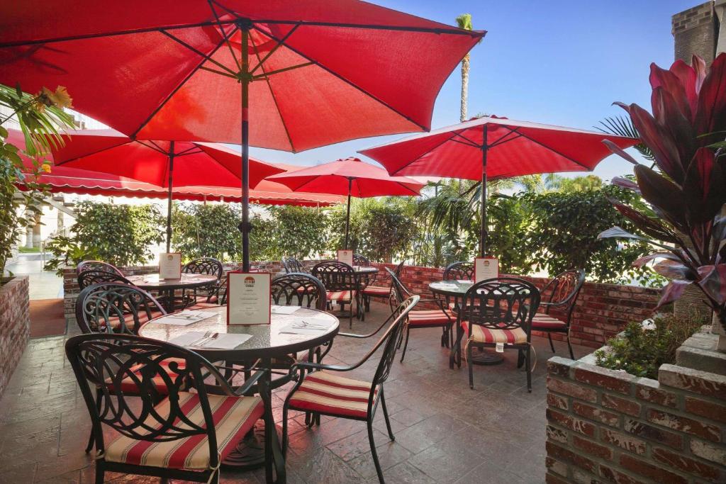 科斯塔梅萨梅萨海岸/纽波特海滩华美达旅馆及套房酒店的一个带桌椅和红伞的庭院