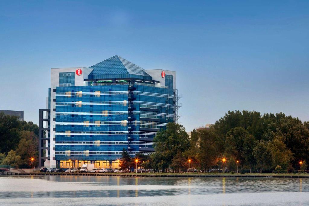 康斯坦察Ramada by Wyndham Constanta的倒映在水中的大型办公楼