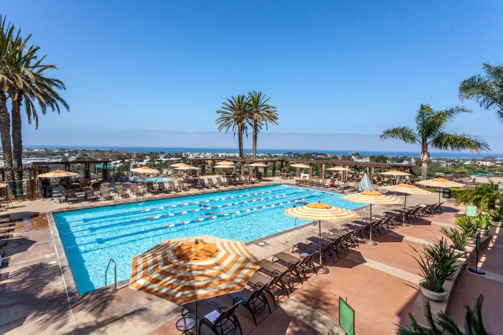 卡尔斯巴德Grand Pacific Palisades Resort的一个带遮阳伞和桌椅的游泳池