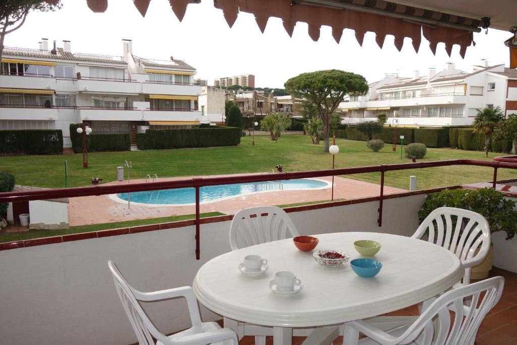 卡莱利亚德帕拉弗鲁赫尔Apartament Calella Park的一个带游泳池的阳台,配有一张白色的桌子和椅子