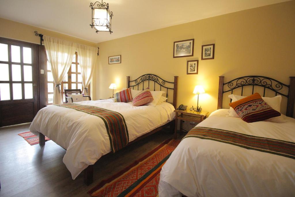 库斯科LLipimpac House的一间卧室设有两张带白色床单的床和窗户。
