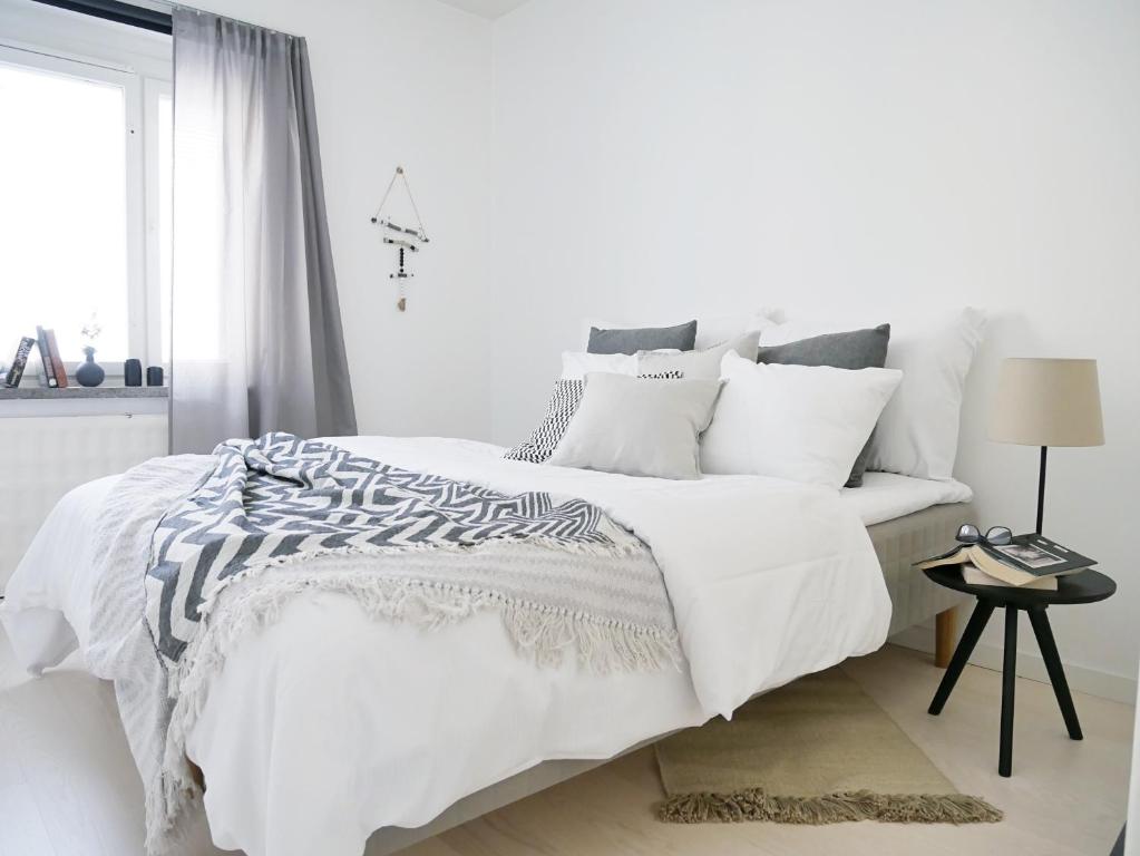 赫尔辛基鲁司特克里斯蒂安公寓的白色卧室配有带白色床单和枕头的床