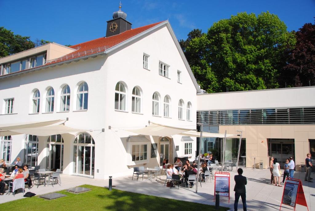 林茨耶格尔梅尔霍夫酒店的一座白色的建筑,外面的人坐在