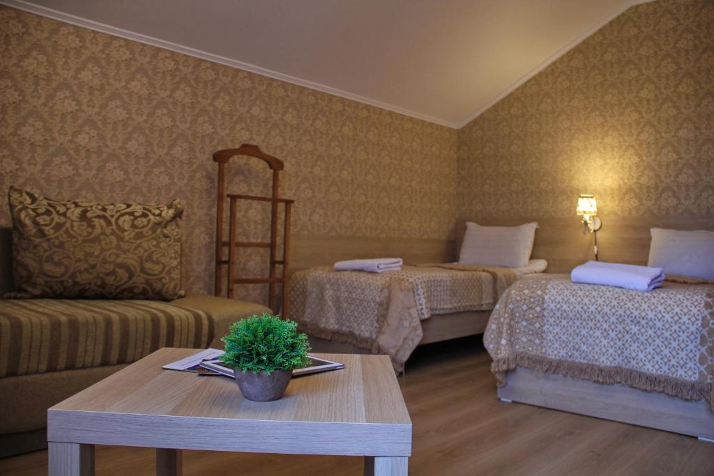 比什凯克拉威提酒店的客房设有两张床、一张桌子和一张沙发。