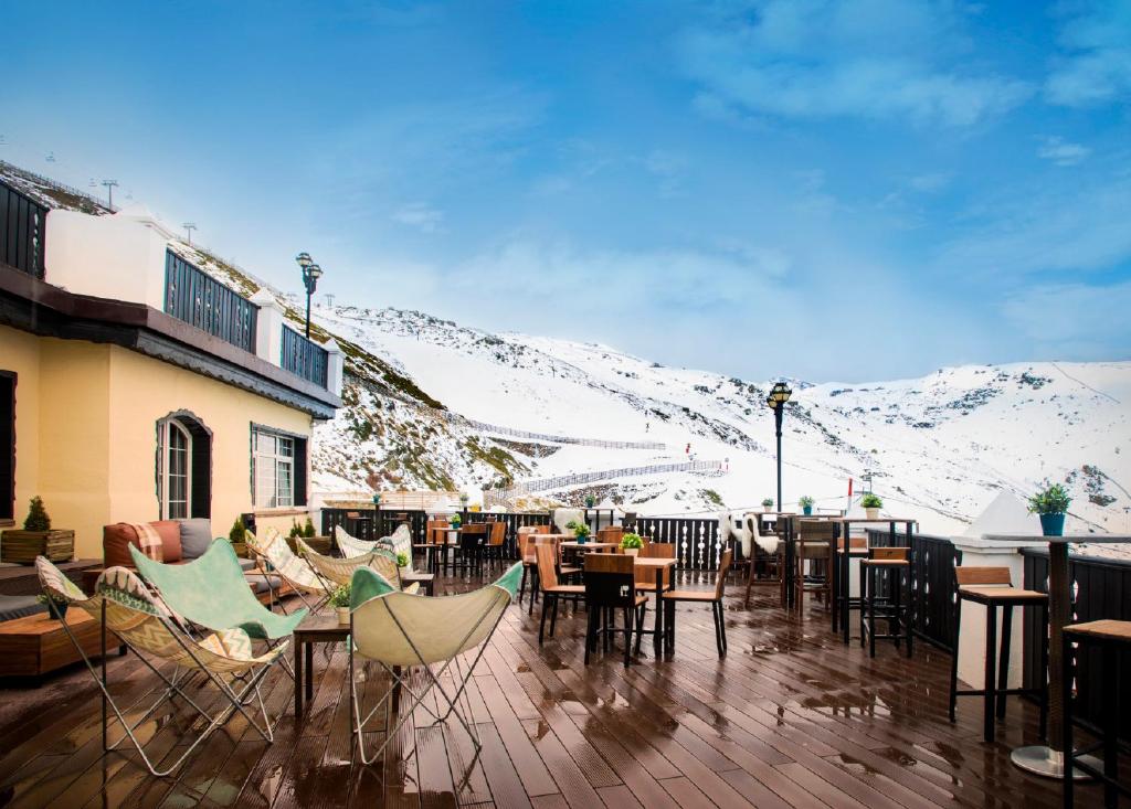 塞拉内华达鲁麦基伊亚精选文奇酒店的一个带桌椅的庭院,以及覆盖着雪的群山